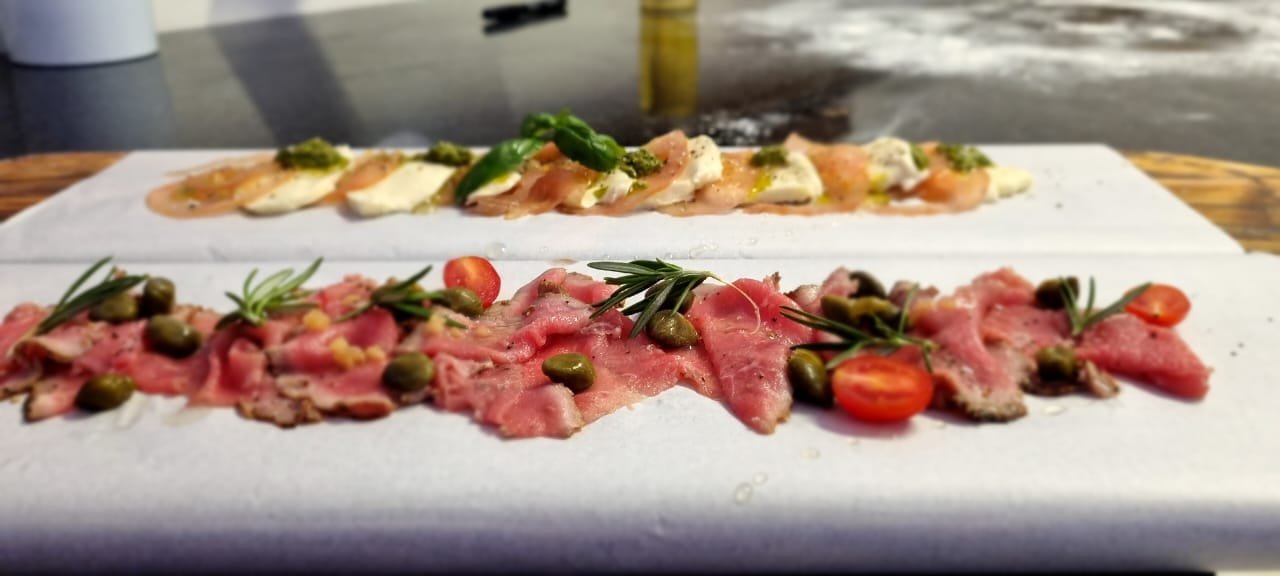 Beef carpaccio and caprese platters, plated on the pass