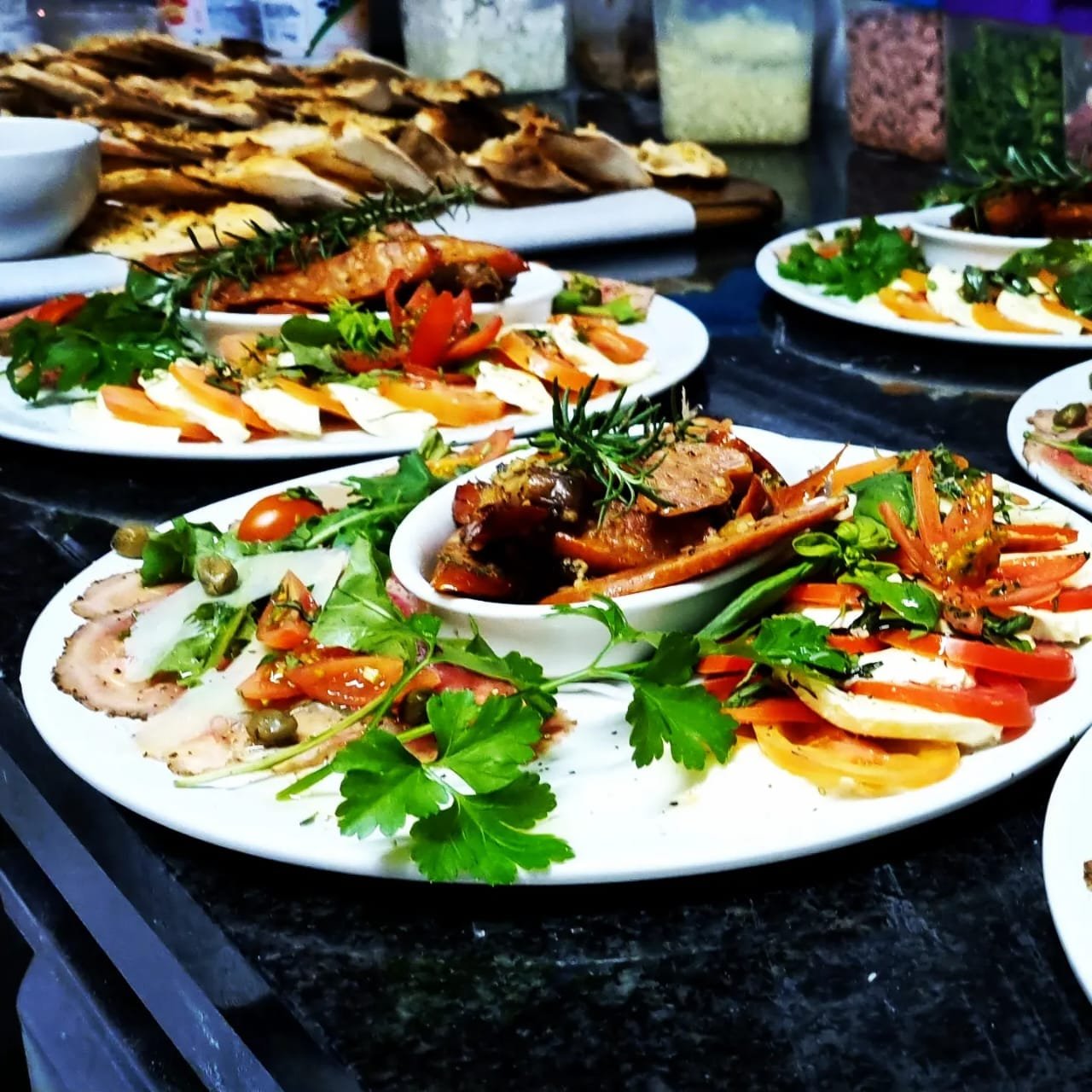 Sharing platters of cured meats, mozzarella, tomato and marinated vegetables
