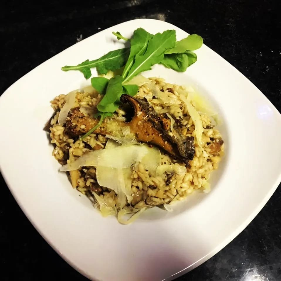 Mushroom risotto topped with shaved parmesan and rocket