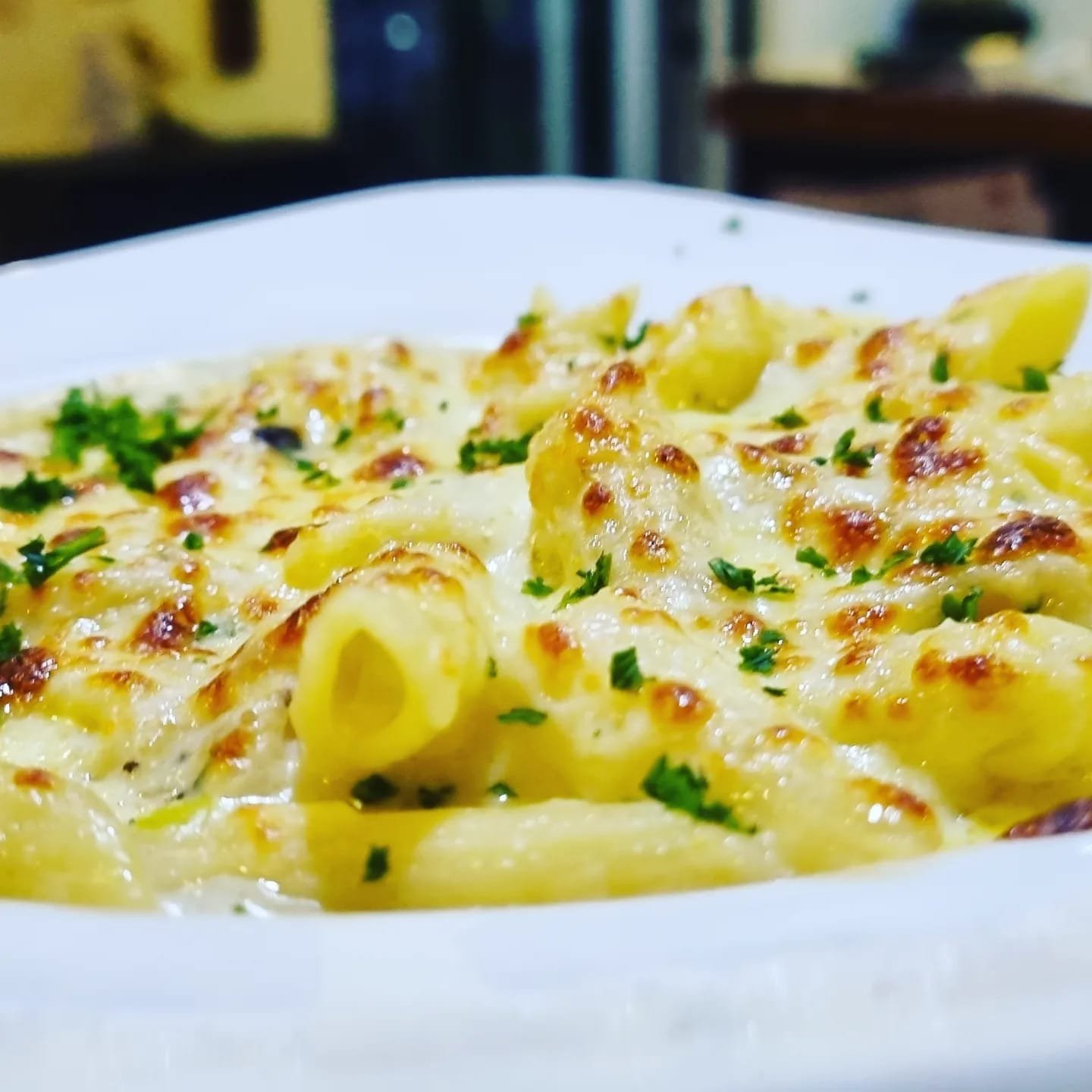Baked penne pasta finished under the grill with melted cheese