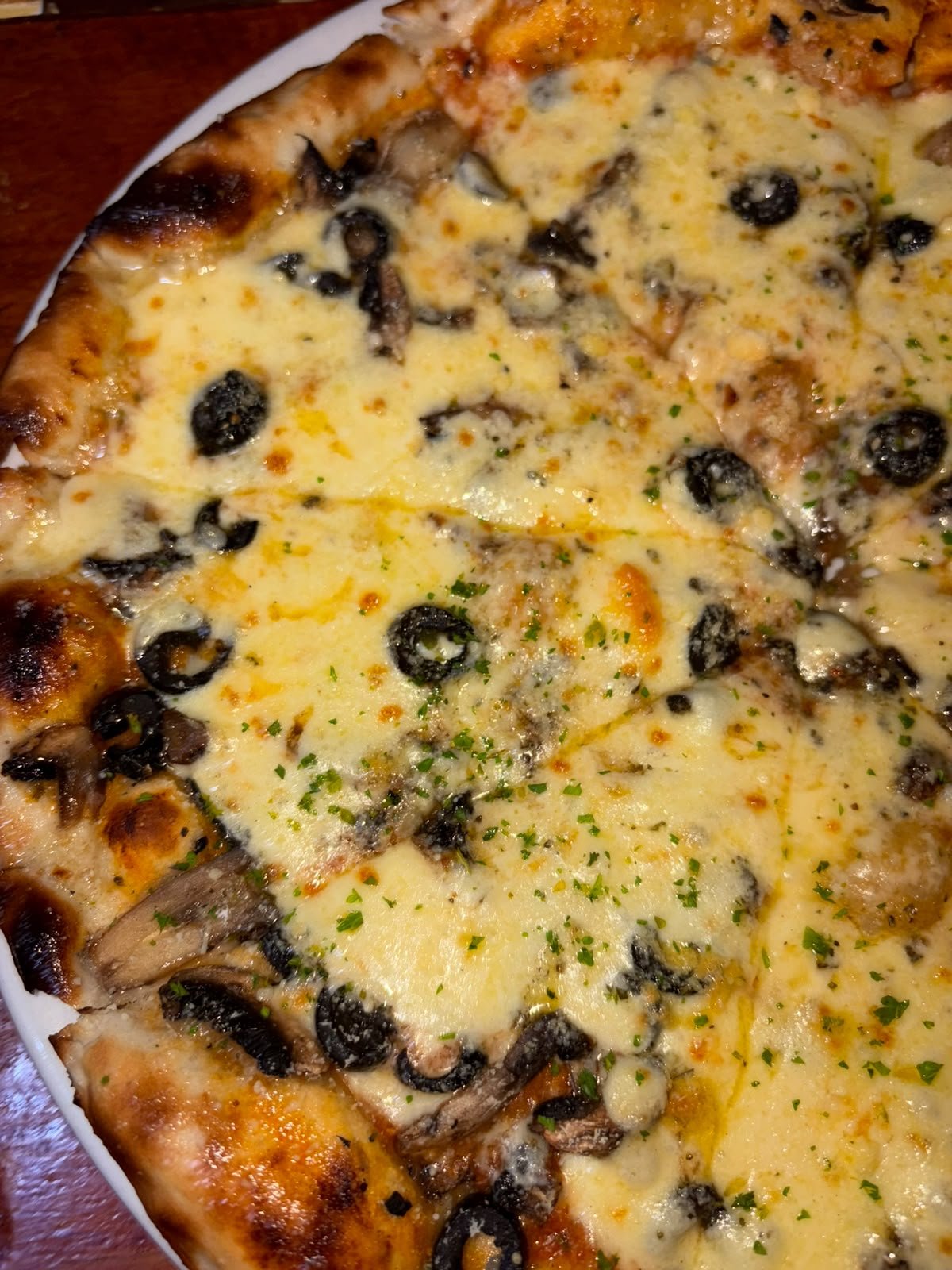 Wood-fired pizza topped with mushroom, olives and melted cheese