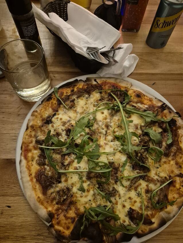Wood-fired pizza topped with melted cheese and rocket at Gavin's Trattoria