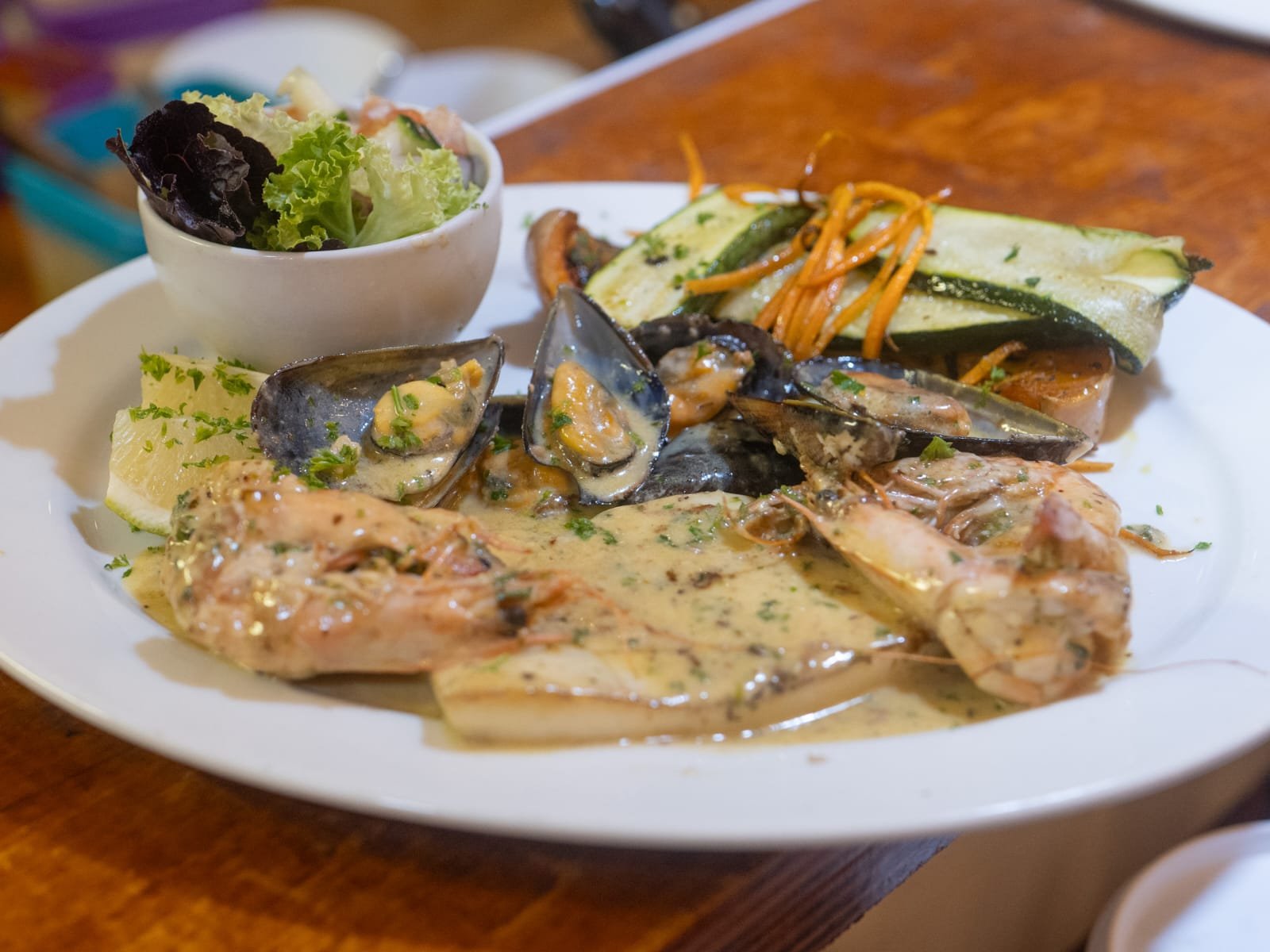 Mussels and prawns in a cream sauce with grilled vegetables and side salad